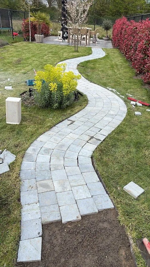 Kronkelend tuinpad in natuursteenkasseien en terras aangelegd door L&R Projects, foto 1 van 4