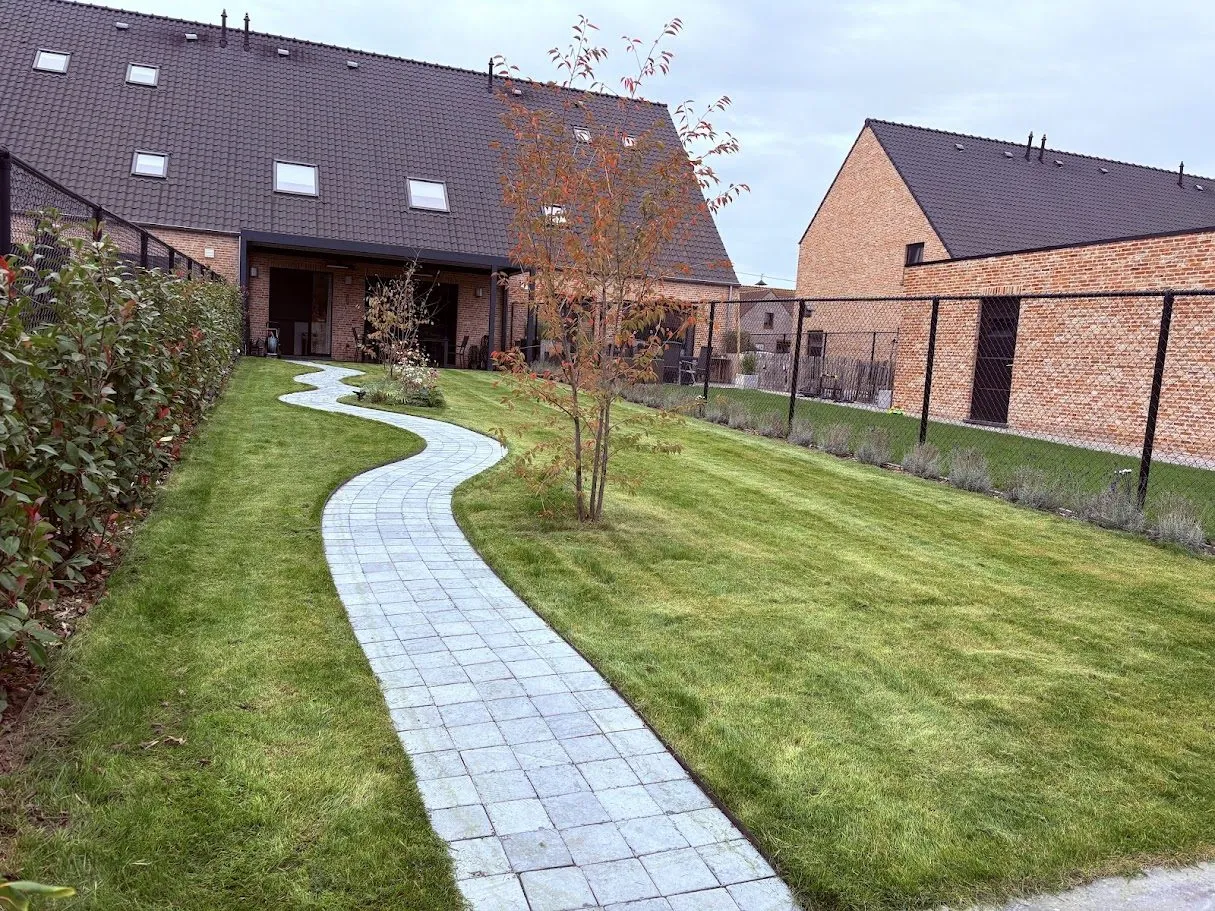 Aangelegde tuin met een kronkelend pad in natuursteen en een nieuw gazon, door L&R Projects